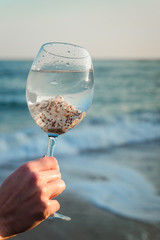 Glass with shells on a background of the sea