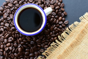 Coffee beans, accompanied by cup of hot coffee