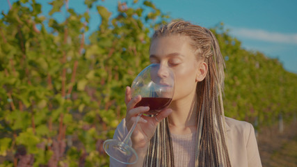 Beautiful woman stand the vineyards with glass of red wine tasting smile feel happy organic connecting with nature agriculture sunny travel countryside field grape green rural close up slow motion