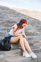 Girl listens to music sitting on stairs in shade