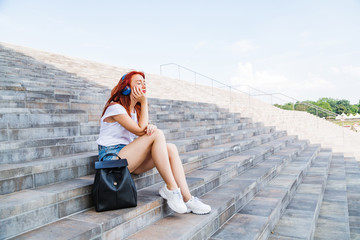 Young girl enjoys sun and music sitting on stairs