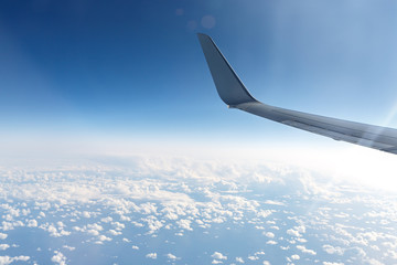 Wing of an airplane in the sky above the blue clouds.