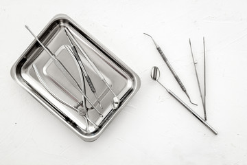 Stomatological tools in tray on dentist's desk on white background top-down