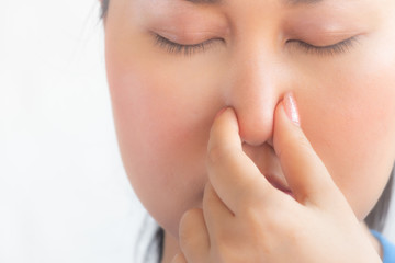 young pretty woman feeling disgusted, holding nose to avoid smelling a foul and unpleasant stench against white  background,asian woman feel smell foul in white background.