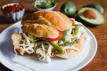 Mexican torta is chicken milanese sandwich with avocado, chili chipotle and oaxaca cheese