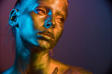 woman golden skin face in bright sparkles, Trendy glowing gold skin make-up. Glitter metallic shine...