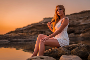 Fototapeta na wymiar A young woman in white dress enjoying a sunset