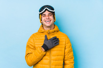 Young skier man wearing snowboard goggles isolated laughs out loudly keeping hand on chest.