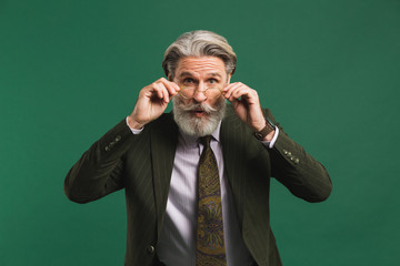 Bearded middle age teacher in khaki suit holds glasses with his hands and blinks his eyes with fun...