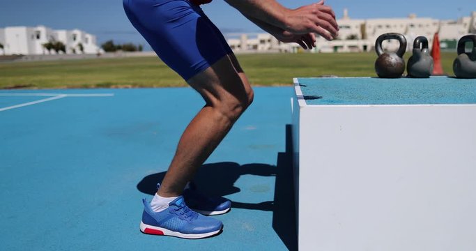 Box Jump training man atlhete jumping doing strength workout outside at outdoor gym at athletics track and field stadium. 59.94 FPS slow motion.