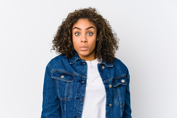 Young african american woman shrugs shoulders and open eyes confused.