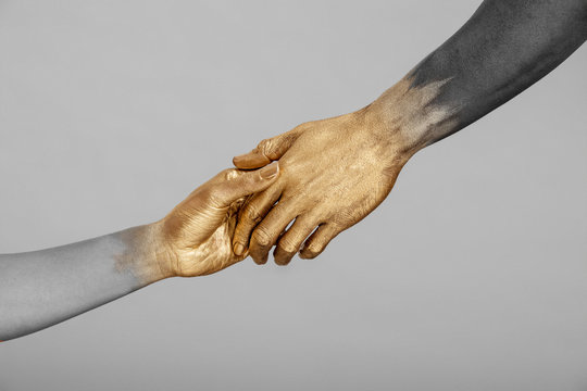 Desaturated shot of mixed-race woman and Black man with gold painted hands holding hands., Dallas, Texas, USA