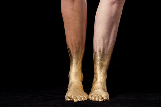 Close-up shot of mixed race and Caucasian women's legs and gold painted feet on black background., Dallas, Texas, USA