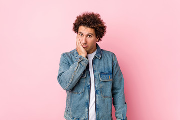 Fototapeta na wymiar Curly mature man wearing a denim jacket against pink background who is bored, fatigued and need a relax day.