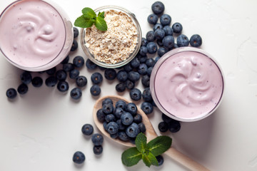 two blueberry yogurt in glasses on a white table, top view, ingredients for cooking diet food