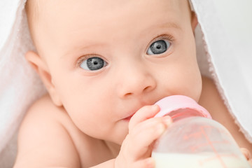 Portrait of cute little baby drinking milk from bottle, closeup