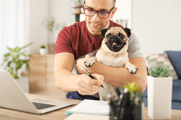 Handsome man with cute pug dog and laptop at home - Powered by Adobe