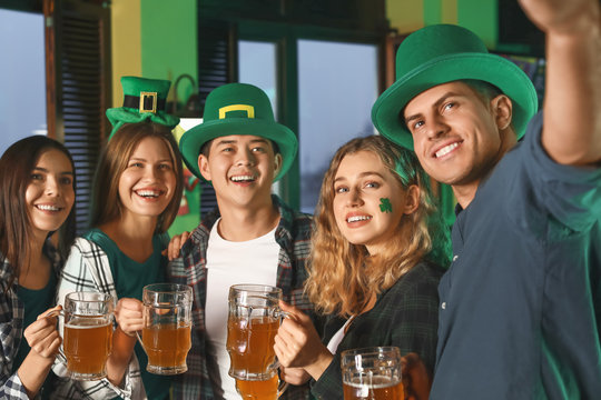 Young friends taking selfie during celebrating St. Patrick's Day in pub