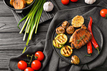 Plate with cooked pork steak and vegetables on table