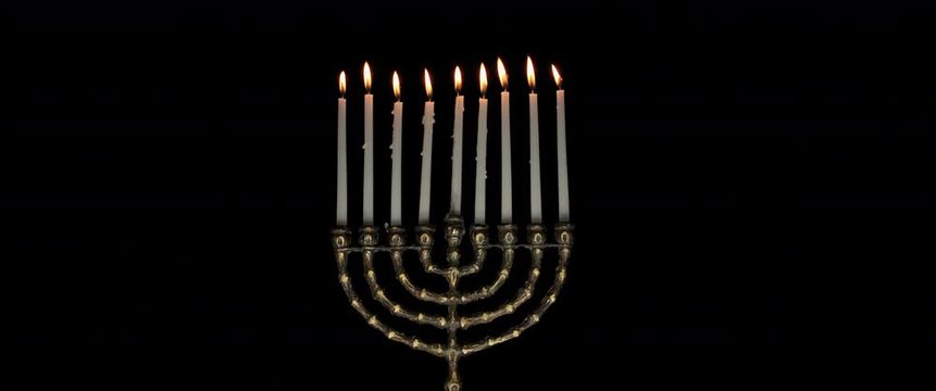Lit Hanukkah menorah candles burning on a dark background, slow motion, BMPCC 4K