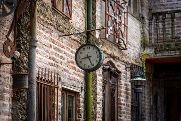 Fototapeta na wymiar GONZALEZ CATAN, ARGENTINA, SEPTEMBER 28, 2019: Very old watch hanging from a brick wall of abandoned building in the amazing medieval town of Campanopolis.