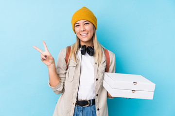 Young caucasian woman holding pizzas isolated joyful and carefree showing a peace symbol with fingers.