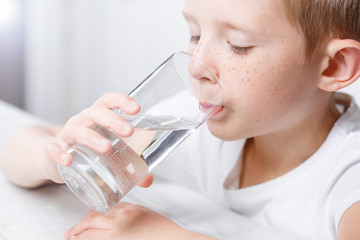 little boy in kitchen drink clean water from glass