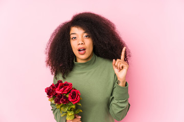 Young afro woman holding a roses isolated Young afro woman holding a roseshaving an idea,...