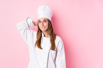 Young caucasian chef woman isolated touching back of head, thinking and making a choice.