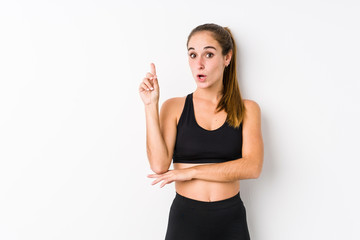 Fototapeta na wymiar Young caucasian fitness woman posing in a white background having some great idea, concept of creativity.