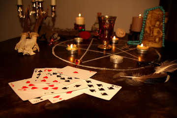 candles are lit in a dark room on a round table, in silver candelabra, fortune-telling cards are...