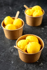 Scoops of yellow ice cream in organic paper cups
