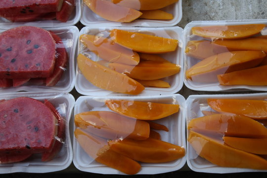 Rebanadas de sand&iacute;a y mango en paquetes blancos de un merca sobre ruedas en la calle