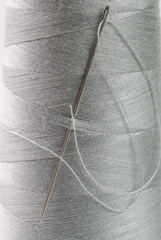 Spool of grey thread and needle macro photography