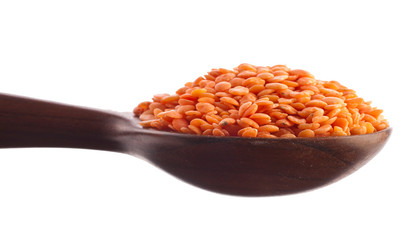 Red lentils in the wooden spoon isolated on a white background.
