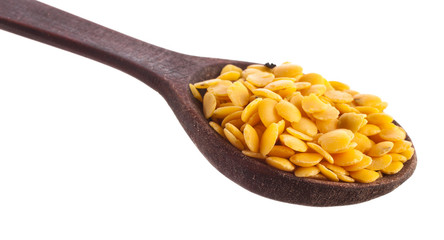 Yellow lentils in the wooden spoon isolated on a white background. Top view.