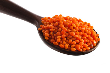 Red lentils in the wooden spoon isolated on a white background. Top view.