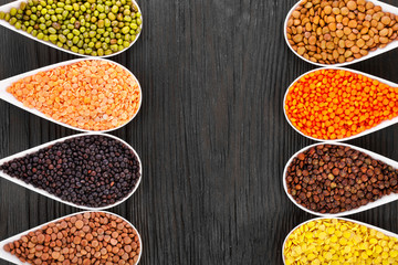 Bowls of various lentils on a wooden background. Top view. Copy space.