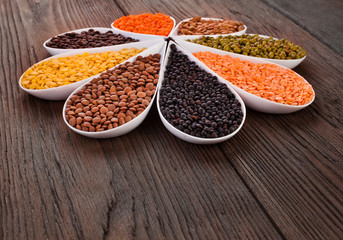 Bowls of various lentils on a wooden background. Copy space.