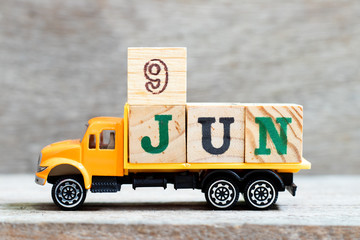 Truck hold letter block in word 9jun on wood background (Concept for date 9 month June)