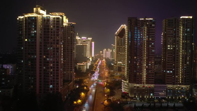 flight over qingdao city downtown night time illuminating show traffic street aerial panorama 4k china