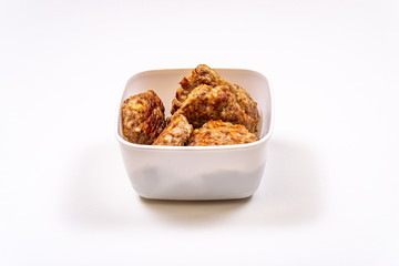 Homemade meat cutlets in a food container on a white table