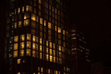 Fototapeta na wymiar Night skyscraper close up, glowing window. Night work.Horizontal frame.