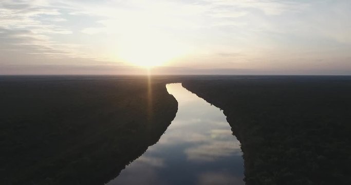 Flying over a river in the amazon jungle during sunrise
