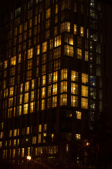 Obraz premium Night skyscraper close up, glowing window. Night work.Vertical shot.