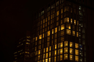 Fototapeta na wymiar Night skyscraper close up, glowing window. Night work.Horizontal frame.