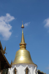 Scenery of golden vintage Buddhist pagoda with cloudy blue sky background. Vertical view. 