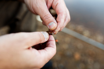 A man is fishing on the river. Fisherman on a morning fishing trip puts the bait on the hook