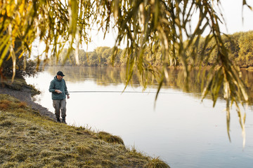 Fototapeta na wymiar A man is fishing on the river. Fisherman on a morning fishing trip