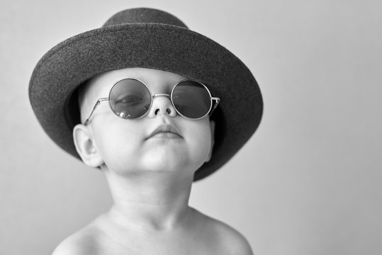 Portrait of a little cute boy in a retro hat and round glasses.